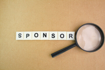 magnifying glass and letters of the alphabet with the word sponsor. sponsorship concept