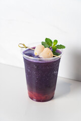 strawberry syrup and butterfly pea juice with fresh lychee on top