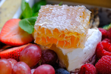 Close up front view of assortment of honey fruits cheeses in a box. Concept for food delivery catering or gift for holiday season or packaging mock up. Selective focus