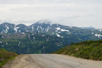 Road on a mountain pass. Mountains in the distance. Summer landscape. Travel and tourism on the Kamchatka Peninsula. Beautiful nature of Siberia and the Russian Far East. Kamchatka Territory, Russia.