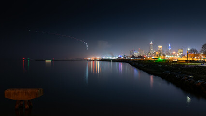 Long exposure landscape shot of city at night with airplane light trail.