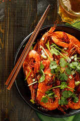 Overhead view of grilled shrimps served with spices and glass of beer over wooden background. Empty space, Copy space.