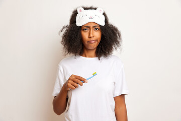 African American woman ready to brush her teeth, holds a toothbrush with boarding look, isolated over white background