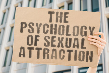 The phrase " The Psychology of Sexual Attraction " is on a banner in men's hands with blurred background. Seductive. Naughty. Dirty. Husband. Hug. Muscular. Naked. Partners. Kissing. Kiss. Playful