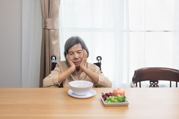 Lonely senior asian woman bored with food.