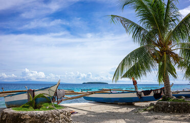 View of the tropical sea with lots of blue sky as copy space. In the foreground are traditional...