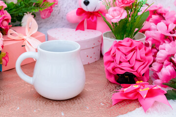 White blank creamer mug on the top of a small rounded table cloth surrounded by valentine themed decorations