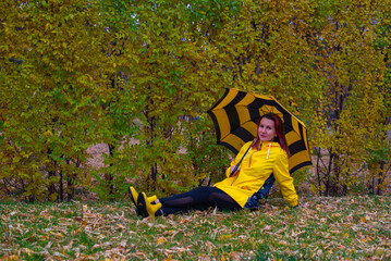 on the autumn lawn a young girl sits with an umbrella
