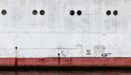 Vintage white ship hull with red waterline and portholes