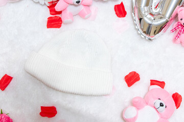 White blank beanie above a fluffy white carpet surrounded by valentine themed decorations