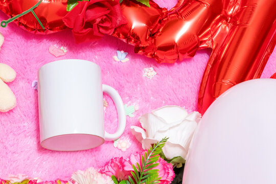 White blank coffee mug on the top of a fluffy pink carpet surrounded by valentine themed decorations
