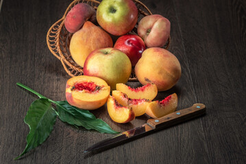 Still life of fresh peaches and apples on a dark background.
