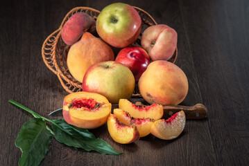 Still life of fresh peaches and apples on a dark background.