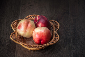Still life of fresh peaches and apples on a dark background.
