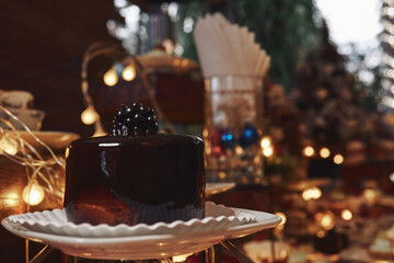 Pastel de chocolate con fondo de adornos navideños, luces cálidas y postres variados