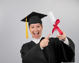 Happy woman in graduate gown pointing finger at received diploma. 