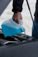 Non-Freezing Liquid For The Car, A man pours glass-washing liquid into the tank of a car