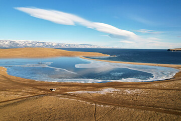Winter landscape from the air. Ice on Lake Khankhoy on Olkhon Island and unfrozen Lake Baikal in December.