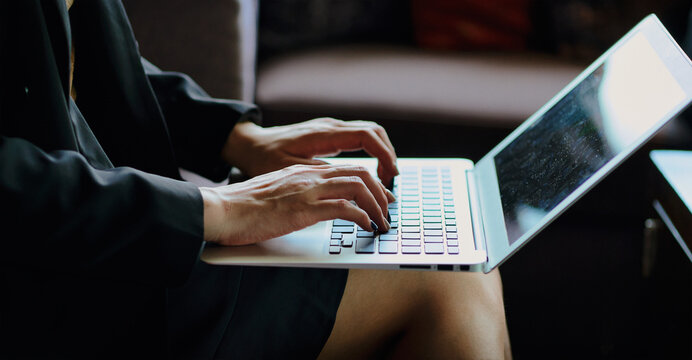 Businesswoman typing on laptop in low light image for business checking