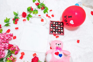 White blank tote bag on the top of a fluffy white carpet surrounded by valentine themed decorations
