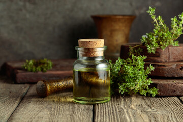 Bottle of thyme essential oil with fresh thyme twigs.