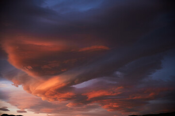 Sunrise with a sky loaded with beautiful clouds with blue and orange colors forming a swirl