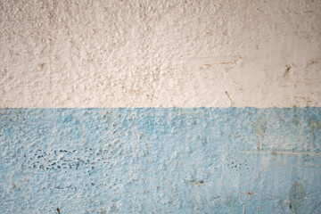 Background with a fragment of a blue-white painted peeled plastered dirty wall