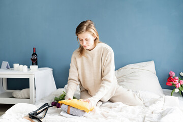 Young woman organizing clothes sitting on the bed at home