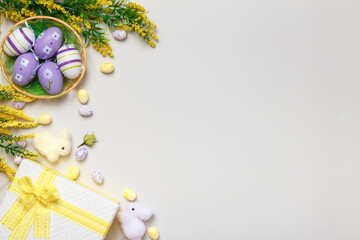 Easter composition. Top view eggs in basket gift flowers on gray background