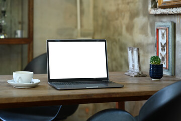 Stylish workplace with laptop computer, coffee cup and potted plant on wooden table