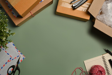 Cardboard boxes, tape and clews of rope on green background with copy advertising space. Top view, Flat lay