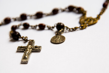 Religious necklace with cross and coin on white paper
