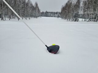 Golf club and golf ball in winter on snow on golf course