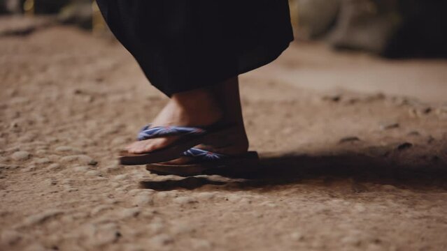 Woman In Wooden Sandals Walking On Rocky Ground