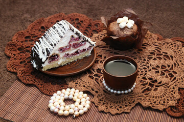 A beautiful still life - a cake, a cup of tea, beads with pearls, cupcakes, on lace napkins.