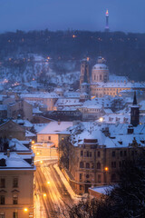 View of Prague roofs with St. Nicolas Church in the background at night in winter. Snow. Prague. Christmas.