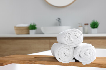 Rolled white towels on tub in bathroom. Space for text