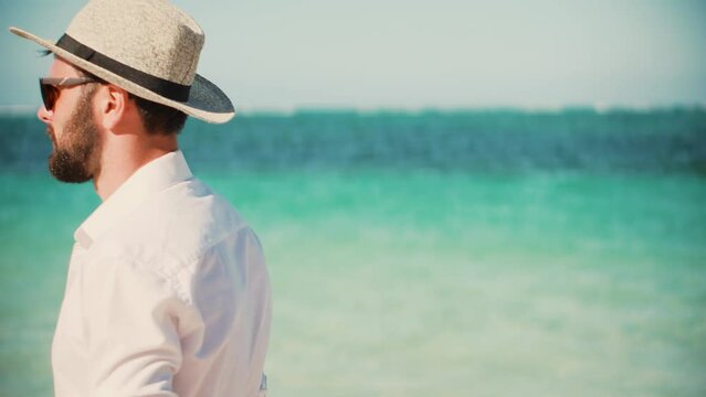 man in hat walking mediterranean sea beach