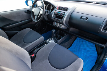 Comfortable front seats inside the car: the driver and passenger, tied with black  textile, retro interior design, the steering wheel covered and a old dirty center console.