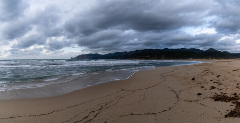panorama landscape of Plagemesu Beach and rugged Sardinian coast under a stormy and overcast sky
