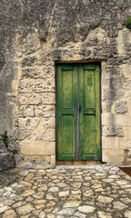 Closed old green wooden door in stone wall