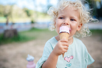 The child eats ice cream in the park in the summer against the backdrop of greenery. Close-up...