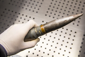 Projectile, cartridge, cartridge case in a man's hand in a rubber glove