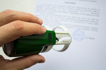 A man's hand holds a seal, a stamp in his hand for documents