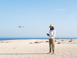 Woman piloting a drone on a sand dunes landscape