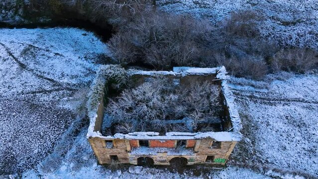 Abandoned house and snowy landscape of cabins and meadows in Puerto de los Tornos, between Cantabria and Burgos. Aerial view from a drone. Castile and Leon, Spain, Europe