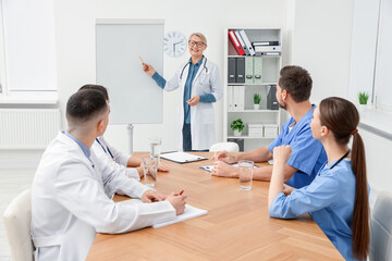 Doctor giving lecture near flipchart in conference room