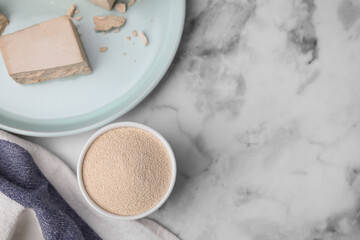 Granulated and compressed yeast on white marble table, flat lay. Space for text