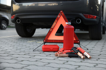 Emergency warning triangle and safety equipment near car, space for text