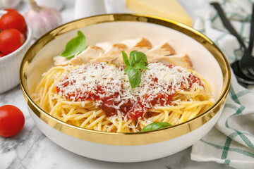 Delicious pasta with tomato sauce, chicken and parmesan cheese on white marble table, closeup